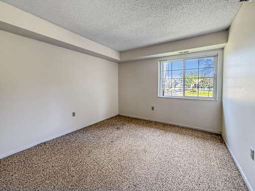 A room with a carpeted floor and a window.