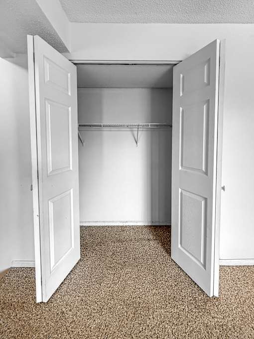 A white door is open to a room with a carpeted floor.