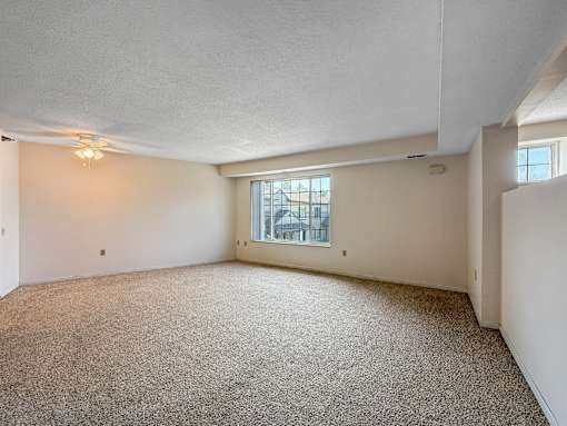 A sparsely furnished room with a carpeted floor and a window.