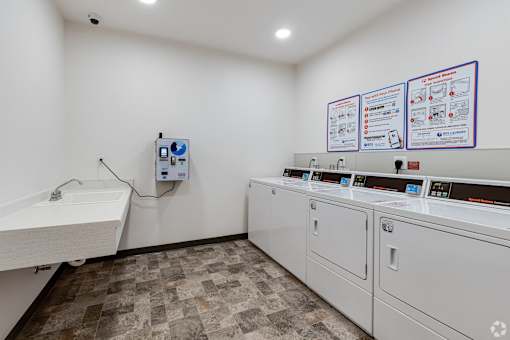 a laundry room at Stryker Senior Apartments in West St. Paul with two washers and two sinks and a counter with two machines