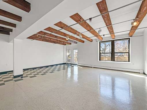 A spacious room with a checkered floor and wooden beams on the ceiling.