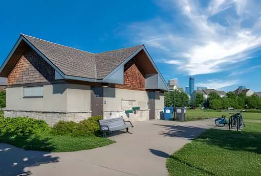 A building with a grey roof and a white wall with a blue bin and a bicycle in front of it.