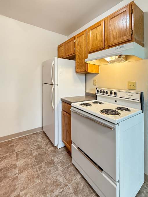 A white stove and refrigerator in a kitchen with wooden cabinets.