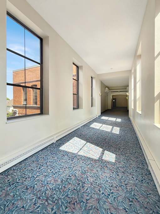 A long hallway with a blue carpet and white walls.