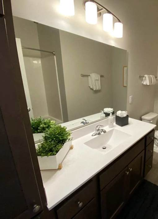 A bathroom with a white counter top and brown cabinets.