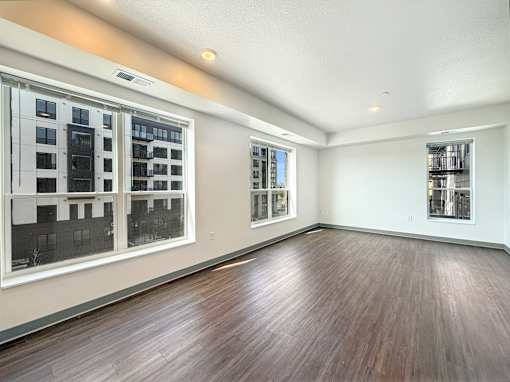 A room with wooden floors and a window overlooking a cityscape at The Lumin in the Highland Park neighborhood of St Paul