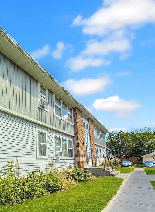 A residential building with a green siding and a brick chimney.
