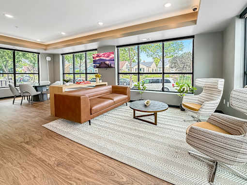 A living room with a brown leather couch and a grey chair.