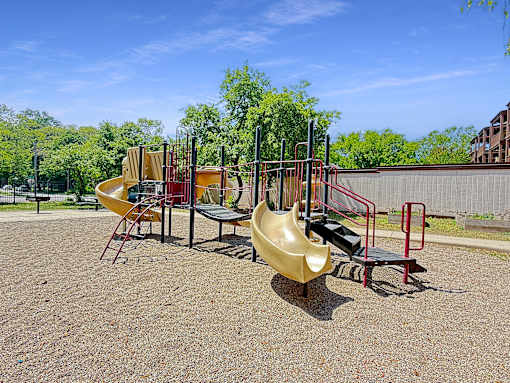 A playground with a yellow slide and red and black equipment.