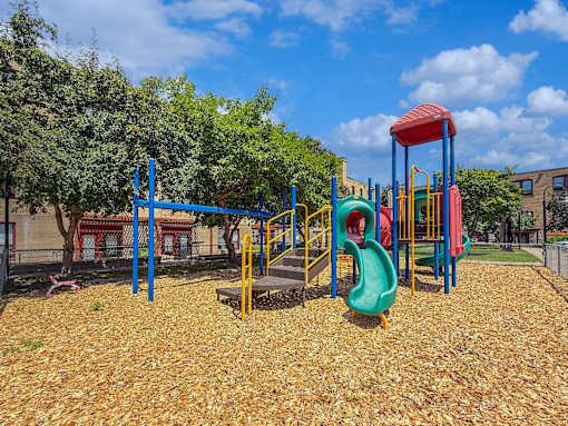 A playground with a red and blue slide and a green slide.