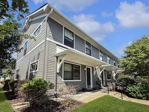 A house with a grey siding and a white porch.