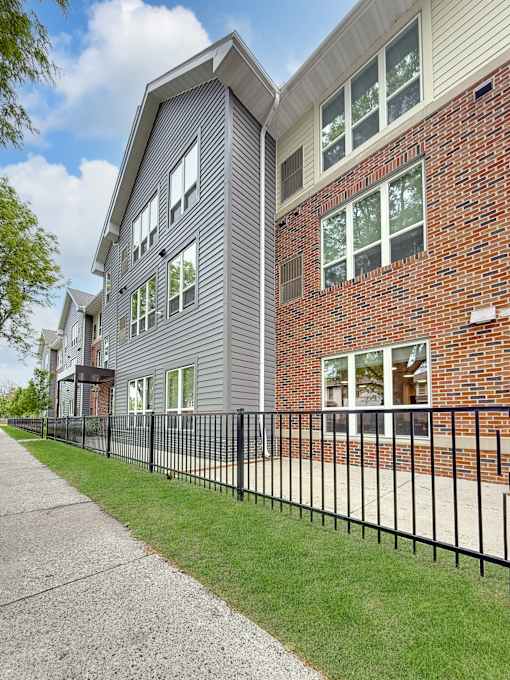 A black metal fence runs along the side of a brick building.