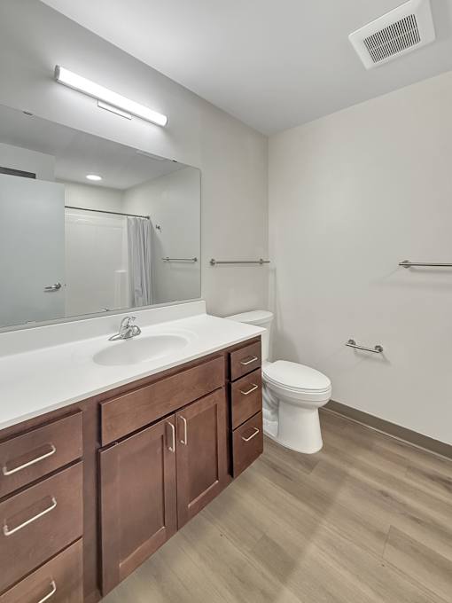 A white sink with a brown cabinet and a white toilet in a bathroom.