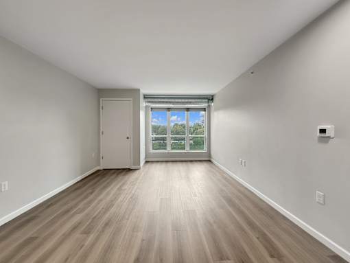 A room with a wooden floor and a sliding glass door leading to a balcony.
