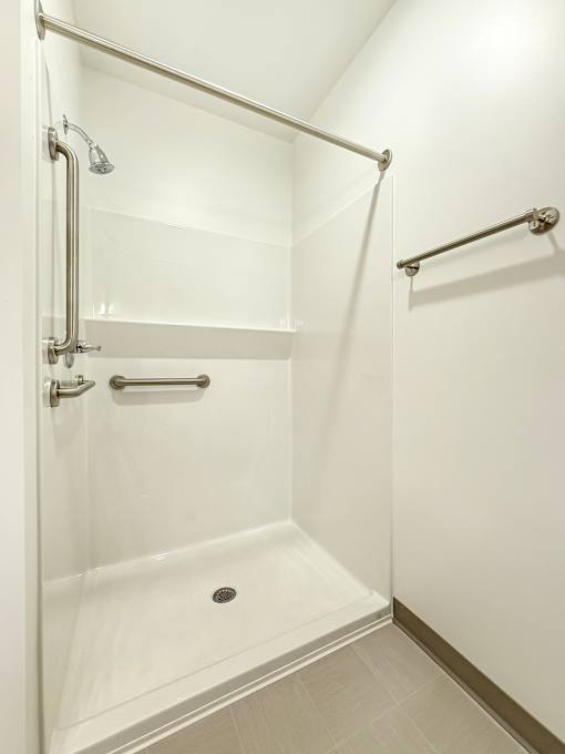 A white shower stall with a glass door and a silver handle.
