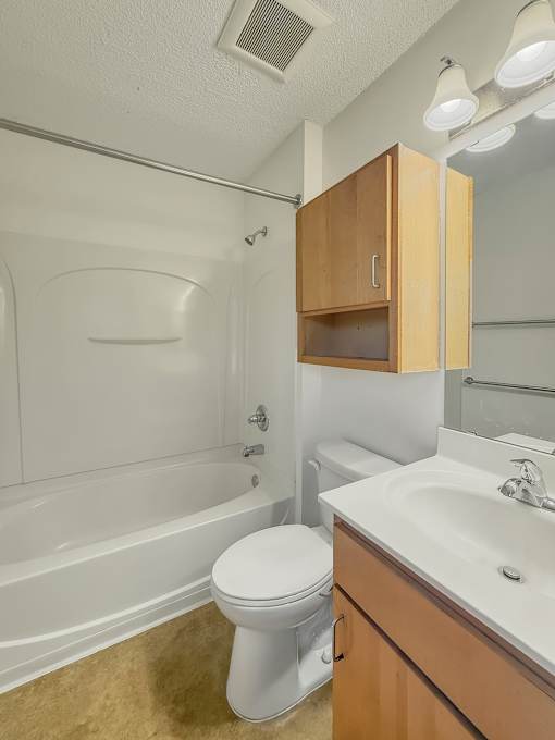 A white toilet sits in a bathroom next to a sink.