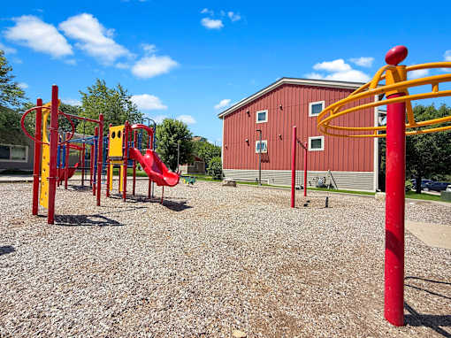A playground with a red slide and a red and yellow structure.