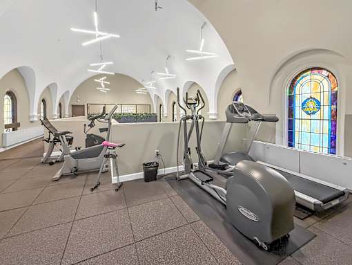 A gym with exercise equipment and stained glass windows.