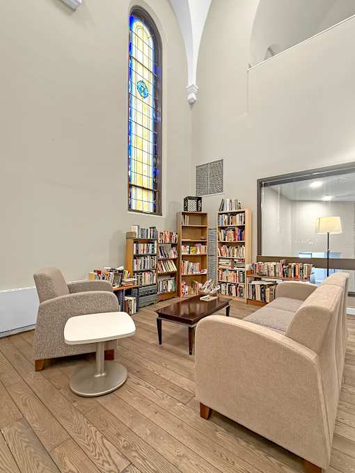 A room with a large stained glass window and a bookshelf filled with books.