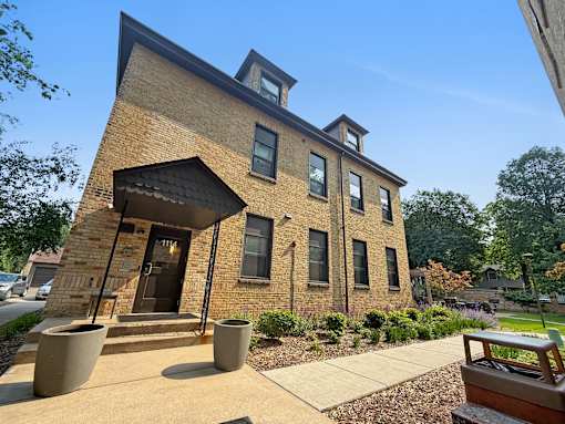 A brick building with a black awning and a small porch.
