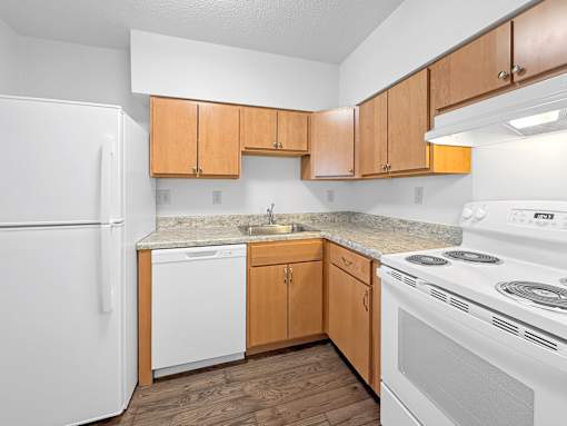 A kitchen with white appliances and wooden cabinets.