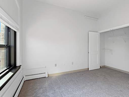 A white room with a carpeted floor and a window.