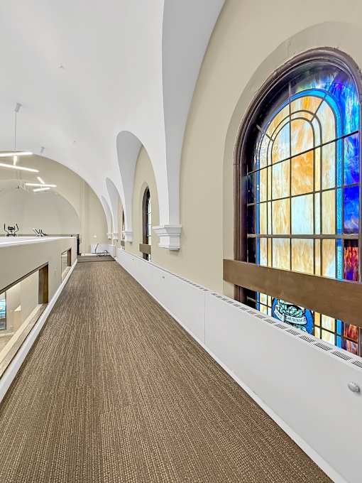 A long hallway with a stained glass window on the side.