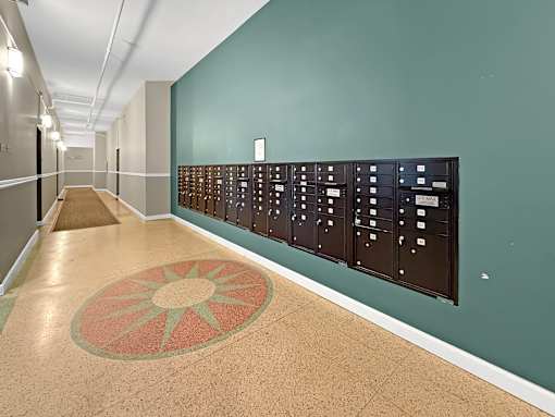 A hallway with a green wall and a long row of mailboxes.