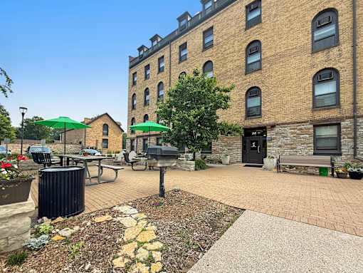 A courtyard with a bench, a table, and a trash can.