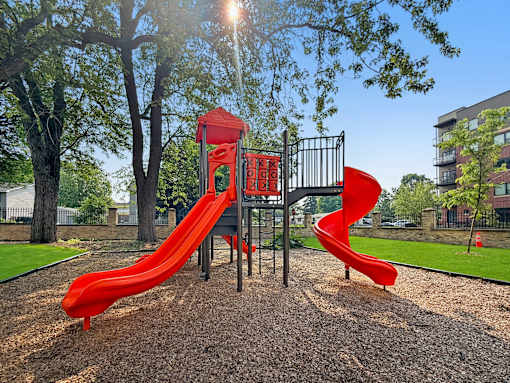 A playground with a red slide and a black metal structure.