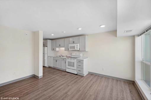 A kitchen with white appliances and wood floors.