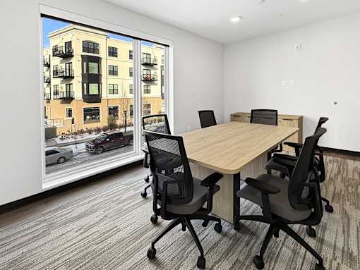 A conference room at The Harken with a table and chairs and a view of a street outside.