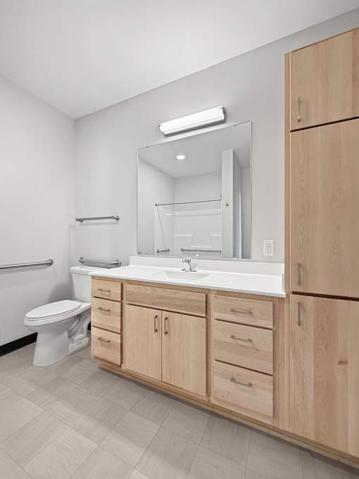 A bathroom at The Harken with a toilet, sink, and mirror.