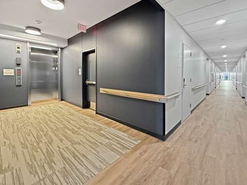 A long hallway with a bench and doors on the left.
