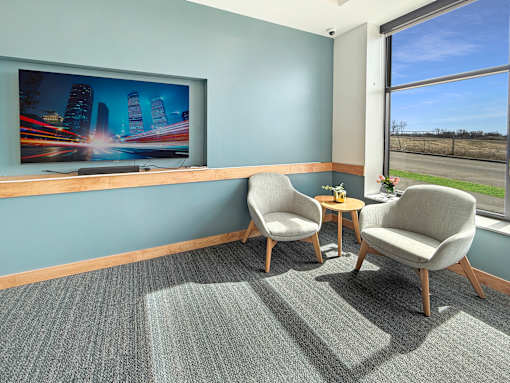 Two chairs and a table are placed in front of a television in a the community room at The Lumin in the Highland Park neighborhood of St Paul.