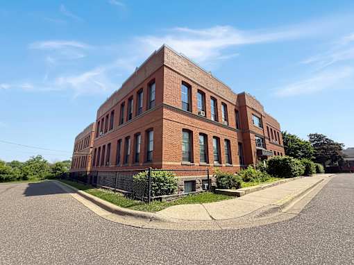 A red brick building with a black fence in front.