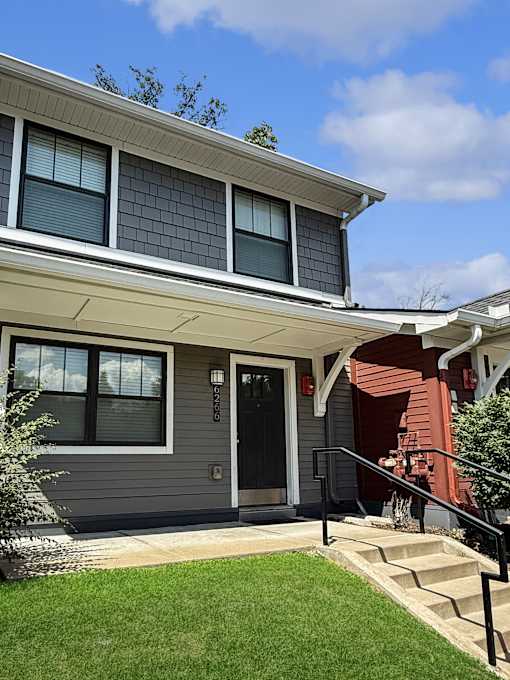 A grey house with a black door and a red door on the side.