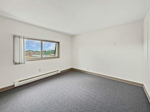 A photo of a Liberty Plaza Townhome bedroom with window and carpeted floor