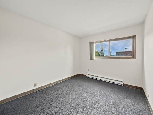 A photo of a Liberty Plaza Townhome bedroom with window and carpeted floor