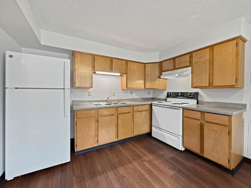 A Liberty Plaza Townhome Kitchen with fridge and range and natural cabinets