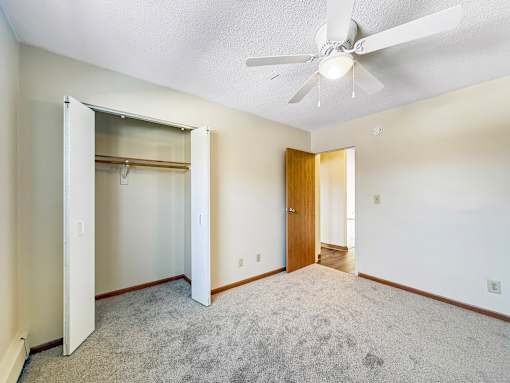A room with a ceiling fan and carpeted floor.
