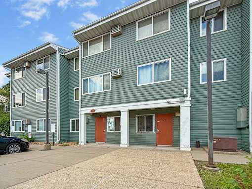 A green apartment building with a red door in the center.