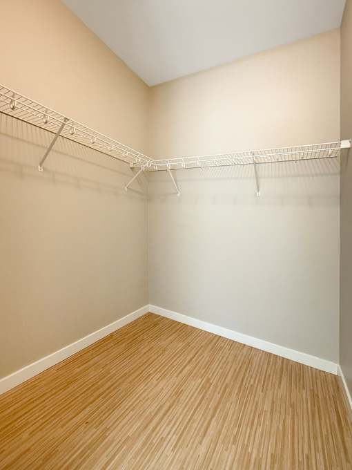 Empty room with white shelves and wood flooring.