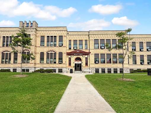 A large building with a red roof and a walkway in front.