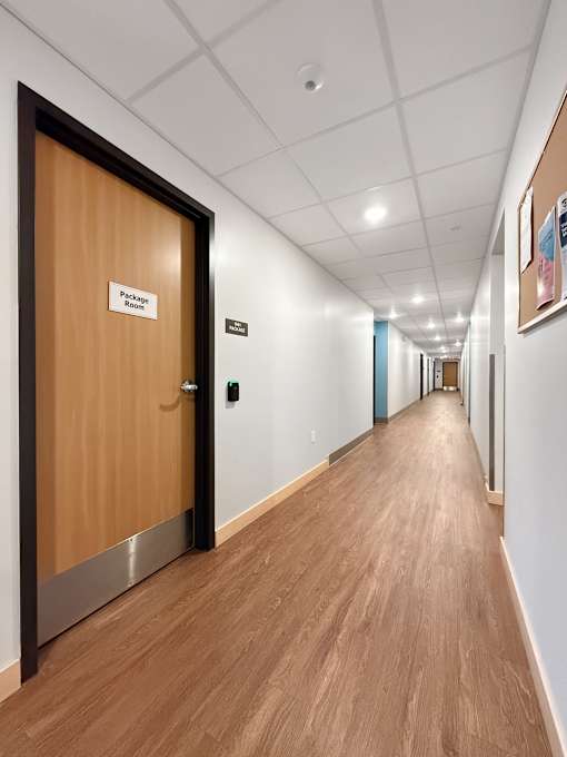 A long hallway with a wooden floor and a door at the end.