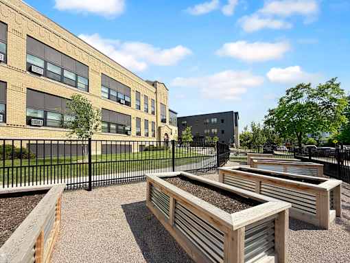 A sunny day at at Whittier with a black fence and raised garden beds.