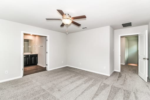 a bedroom with a ceiling fan and a doorway to a bathroom
