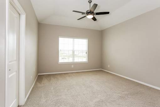 A room with a ceiling fan and a window.