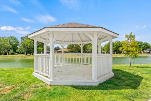 a white gazebo with a pond in the background