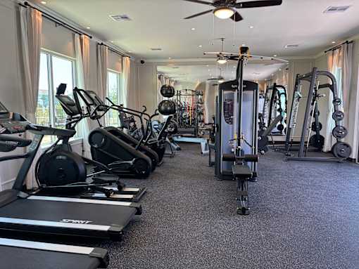 A spacious gym with a variety of equipment including treadmills, elliptical machines, and weight machines.